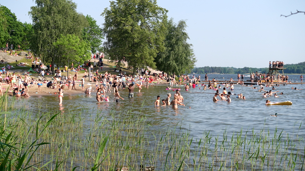 Badplatsen Kanaanbadet i Stockholm - Bilden visar massor av badande människor en fin sommardag.